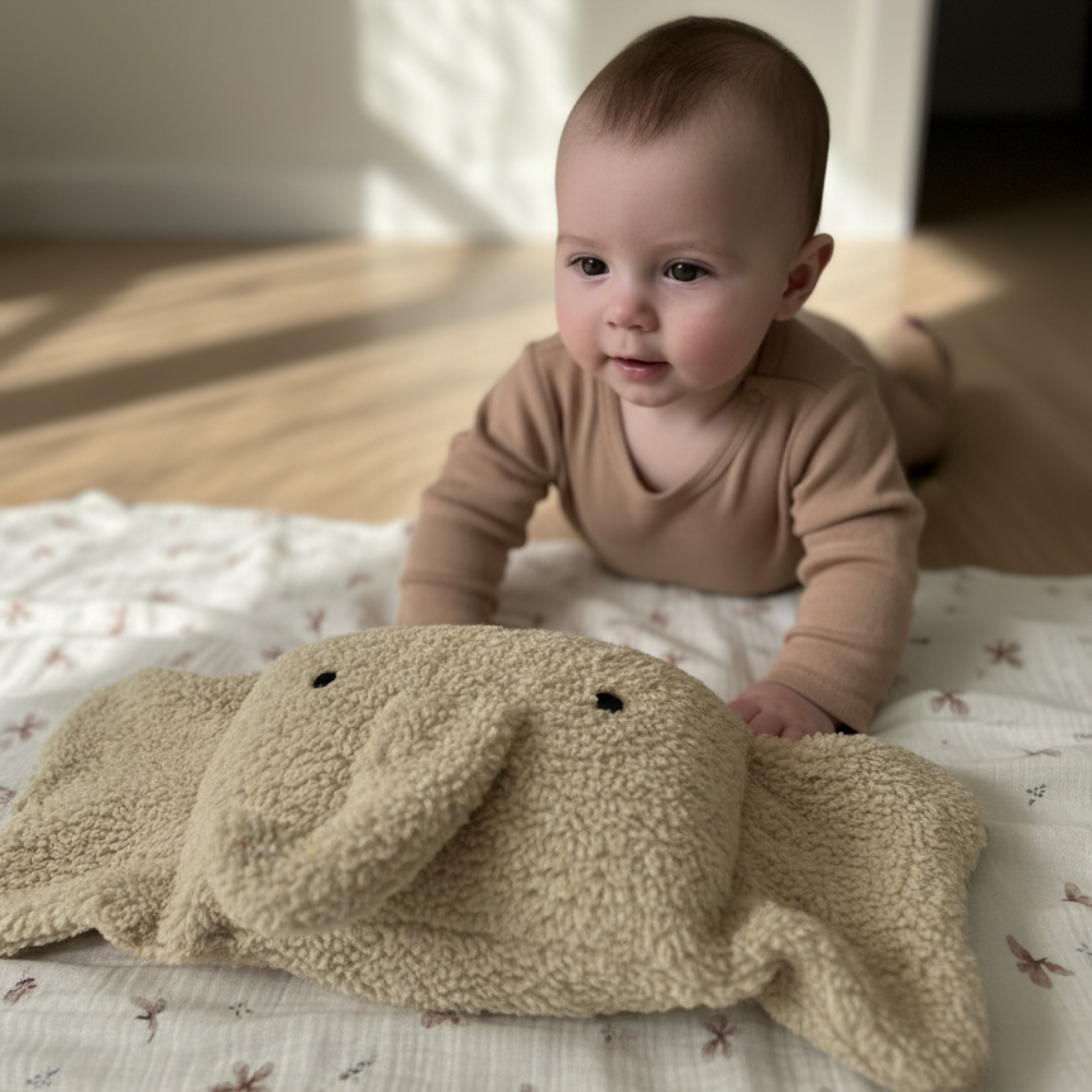 A curious baby playing with Ellie the Elephant Sleep Companion — a handcrafted plush elephant designed to inspire gentle sensory exploration and calm connection.