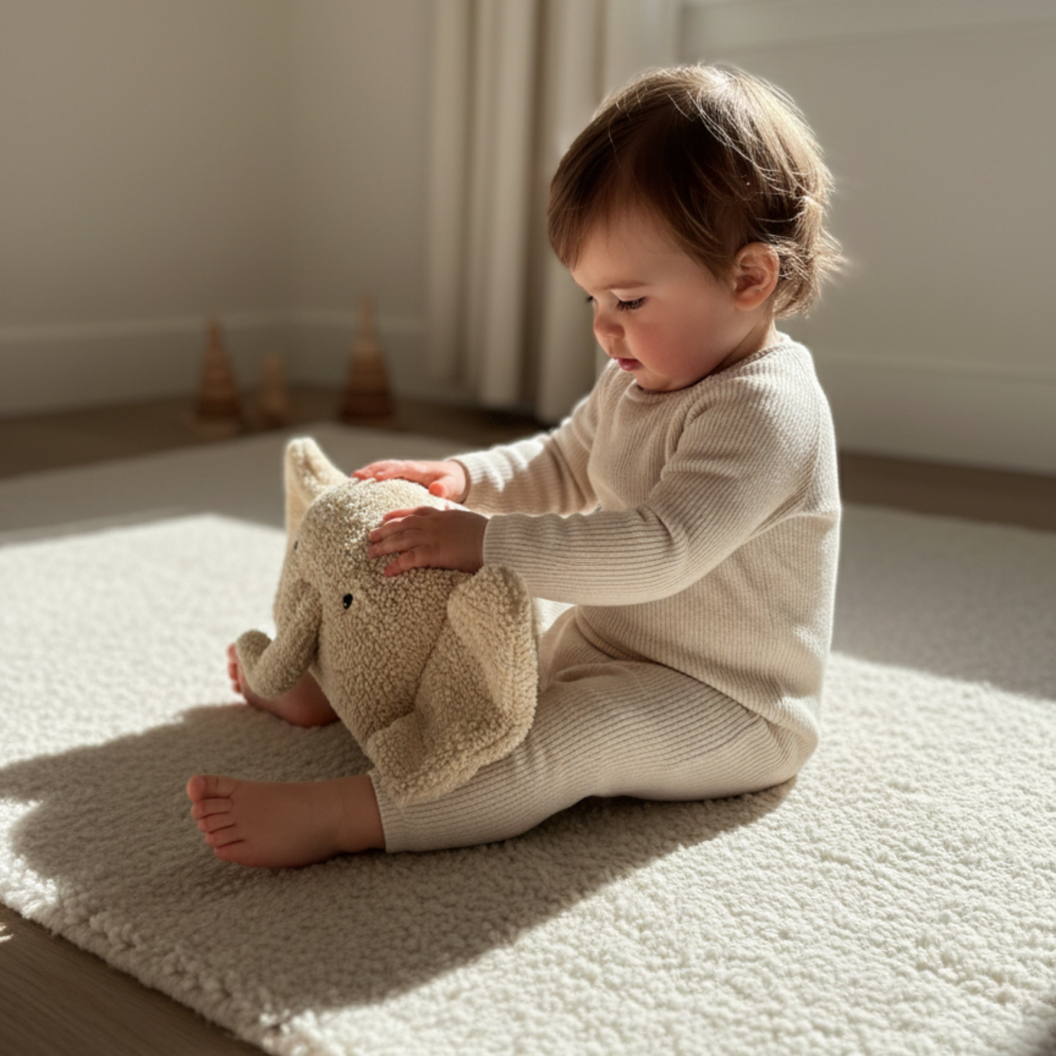 A toddler gently holding Ellie the Elephant Sleep Companion — a handmade plush elephant encouraging calm exploration and sensory growth in early play.