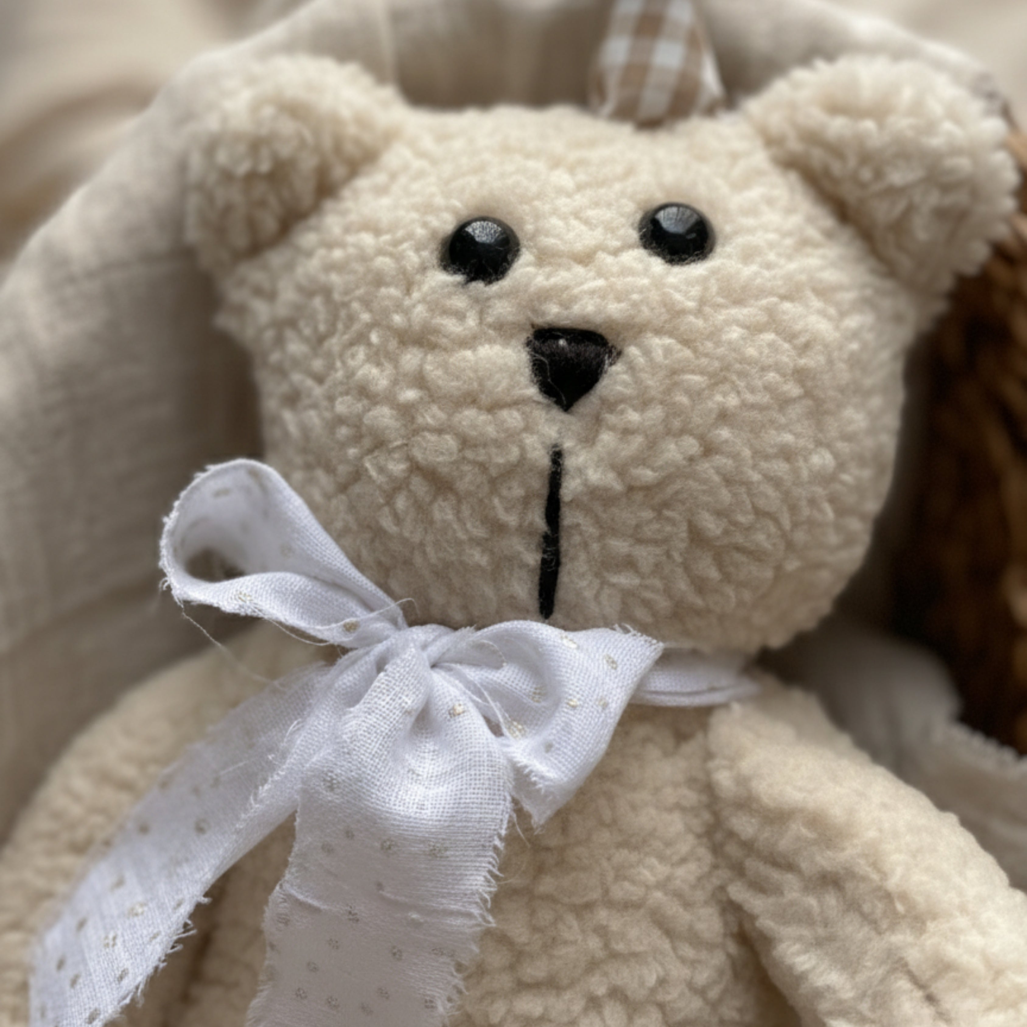 Close-up of Leni the Bear Sleep Companion showing soft organic plush texture, safety eyes, and a handmade cotton bow — crafted for gentle comfort.