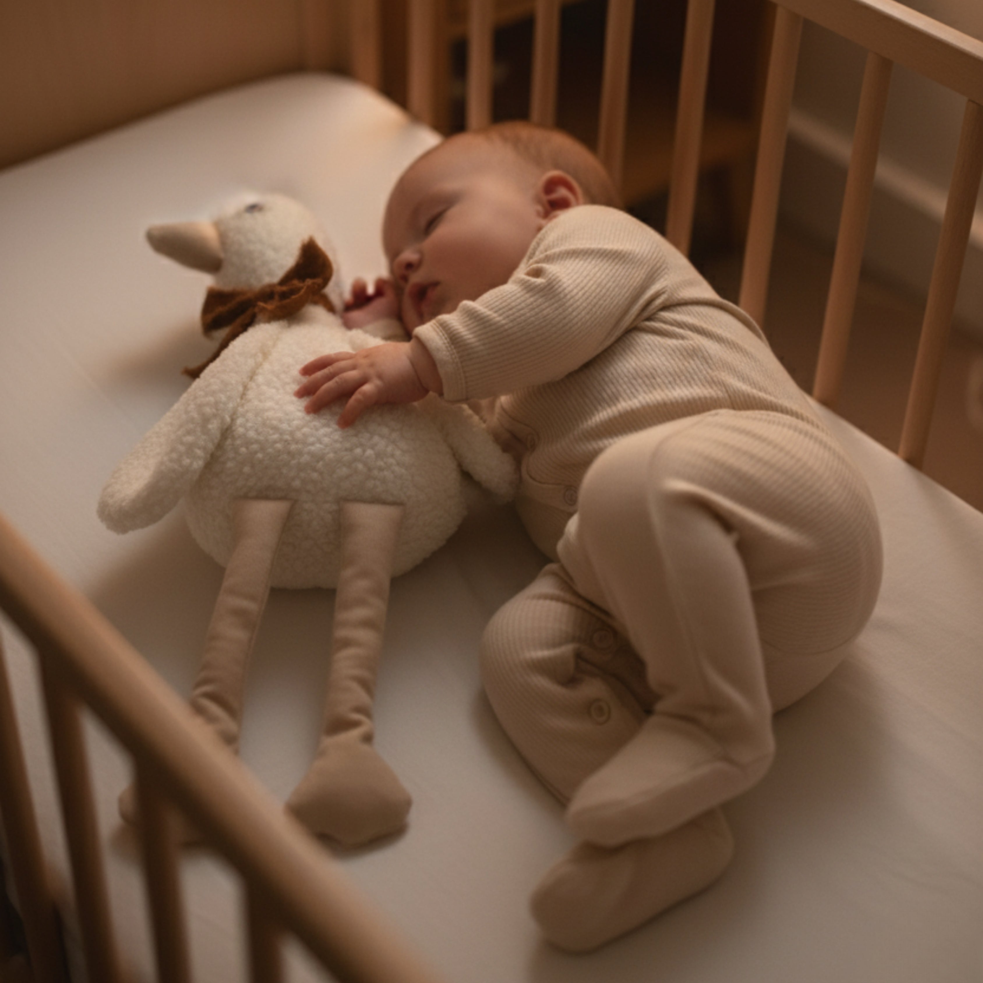 A baby peacefully sleeping in a crib while cuddling Lenny the Duck Sleep Companion — a handcrafted plush duck designed to bring comfort, safety, and serene sleep.