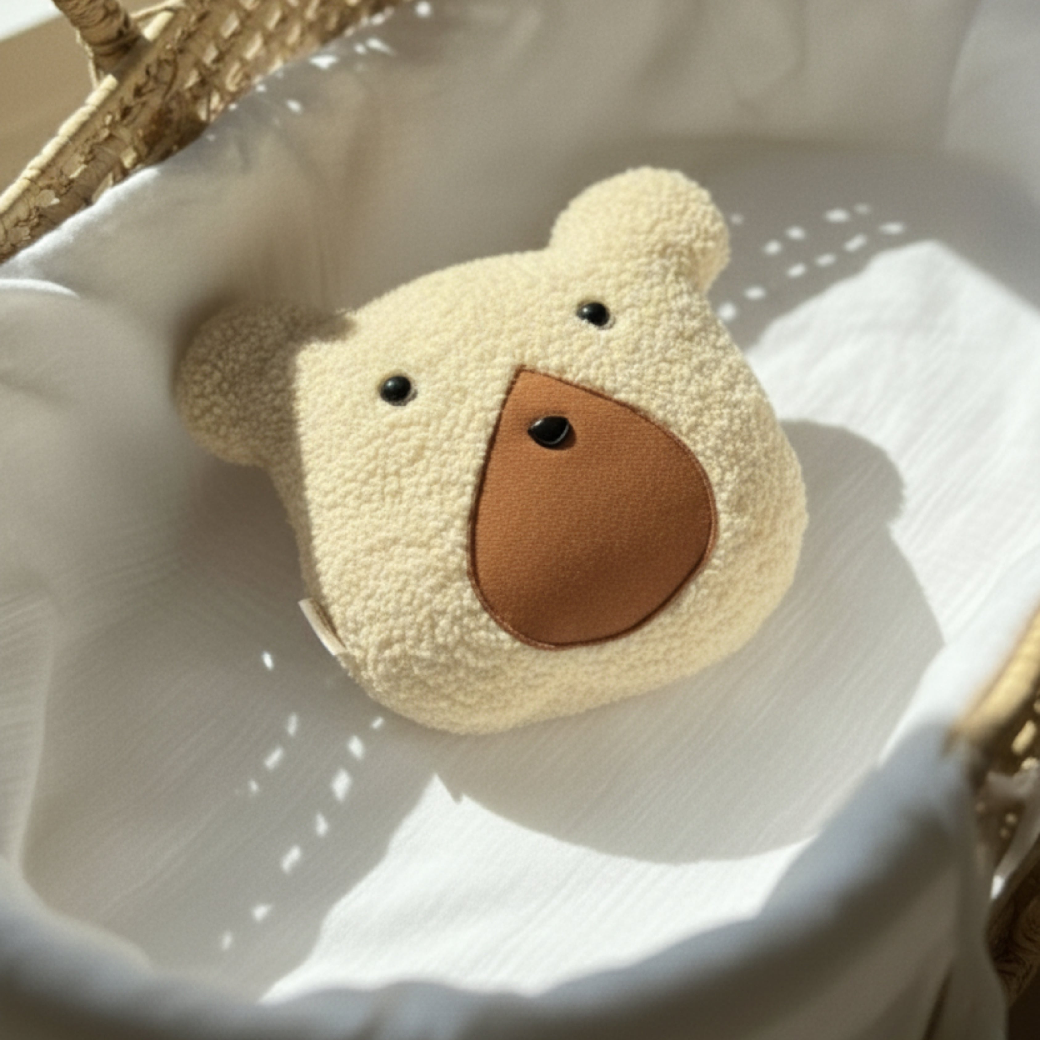 Nino the Bear Sleep Companion resting in a woven bassinet under soft daylight — an organic plush toy designed for baby comfort and gentle sleep.